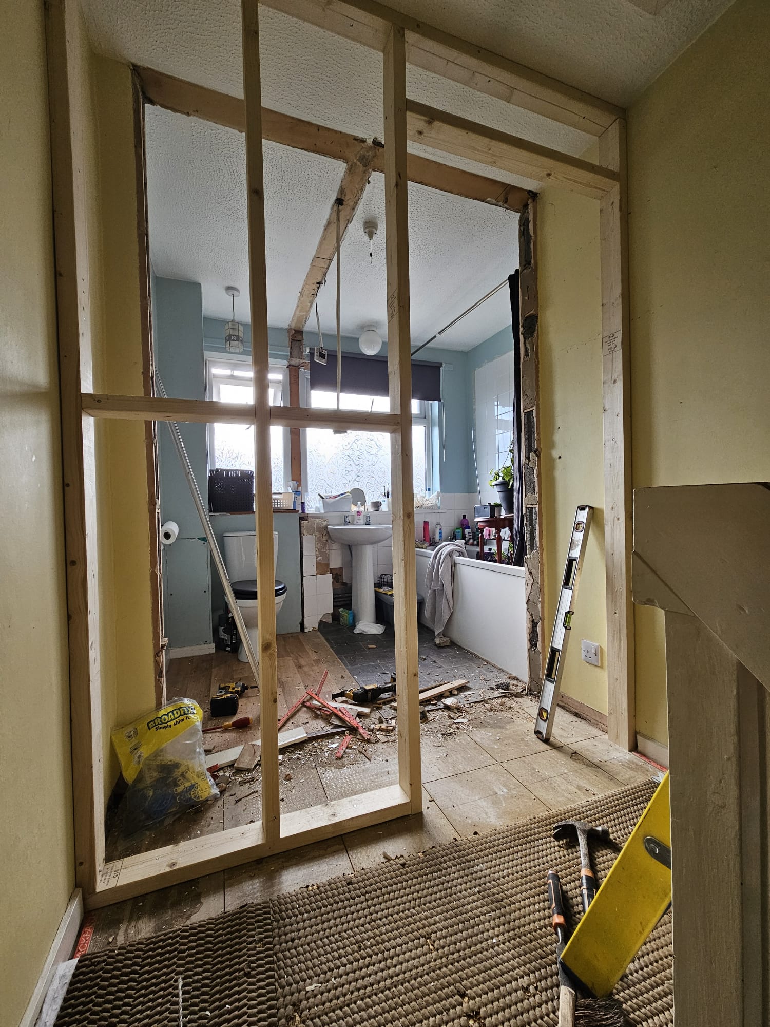 Stud wall opened up between a separate WC and bathroom, mid-conversion