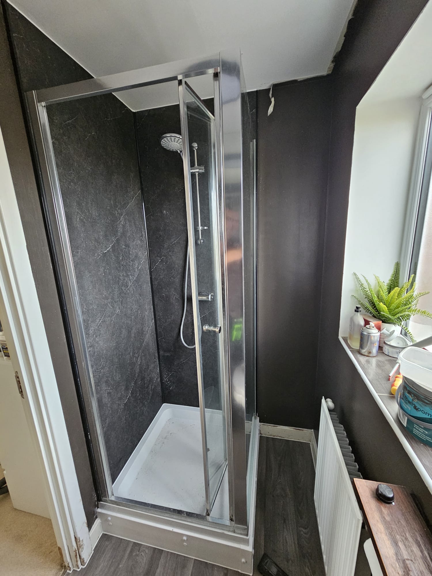 Compact rental bathroom with new shower cubicle and dark slate panel walls