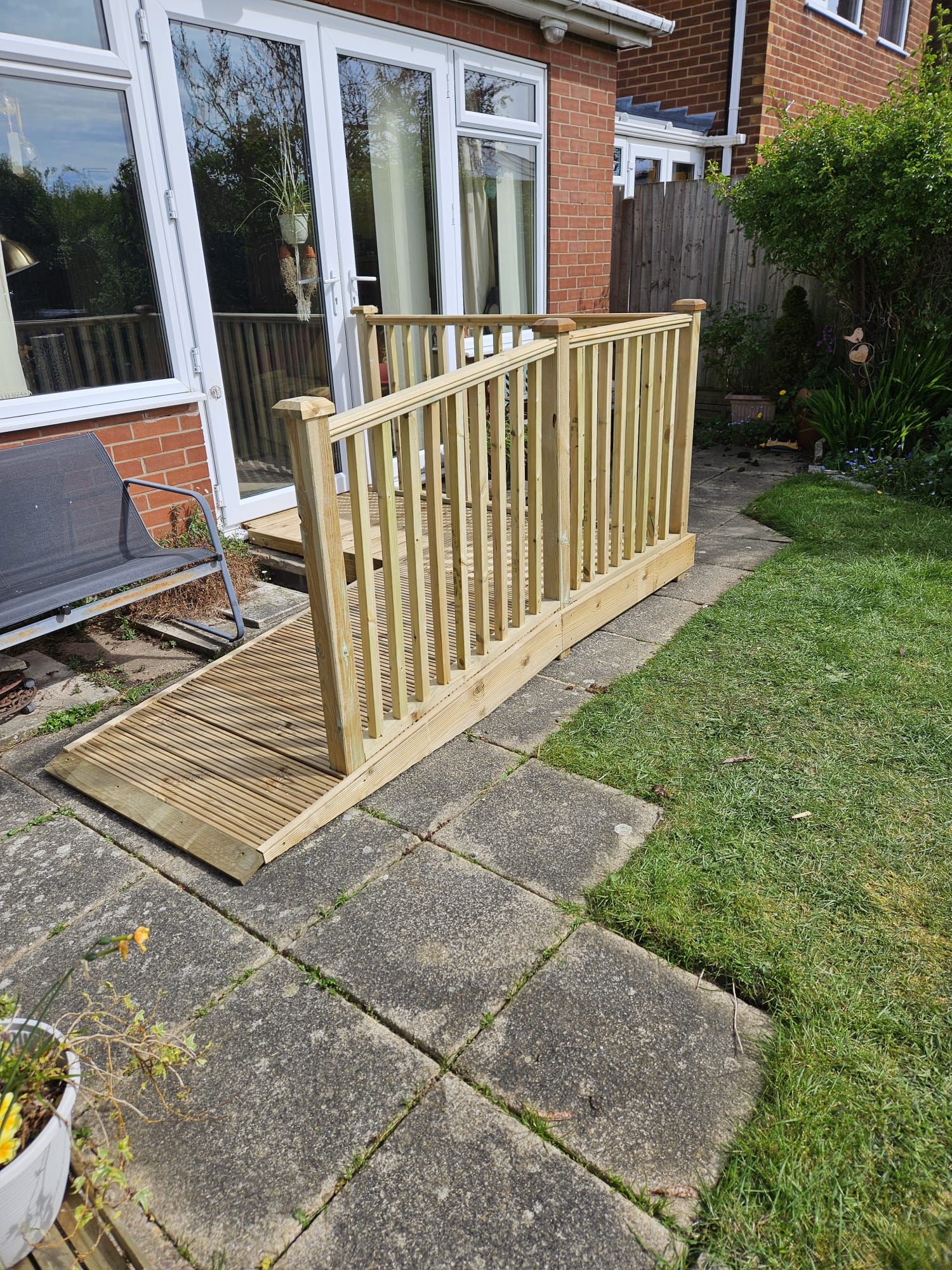 Decking timber wheelchair ramp with handrail leading to back patio doors