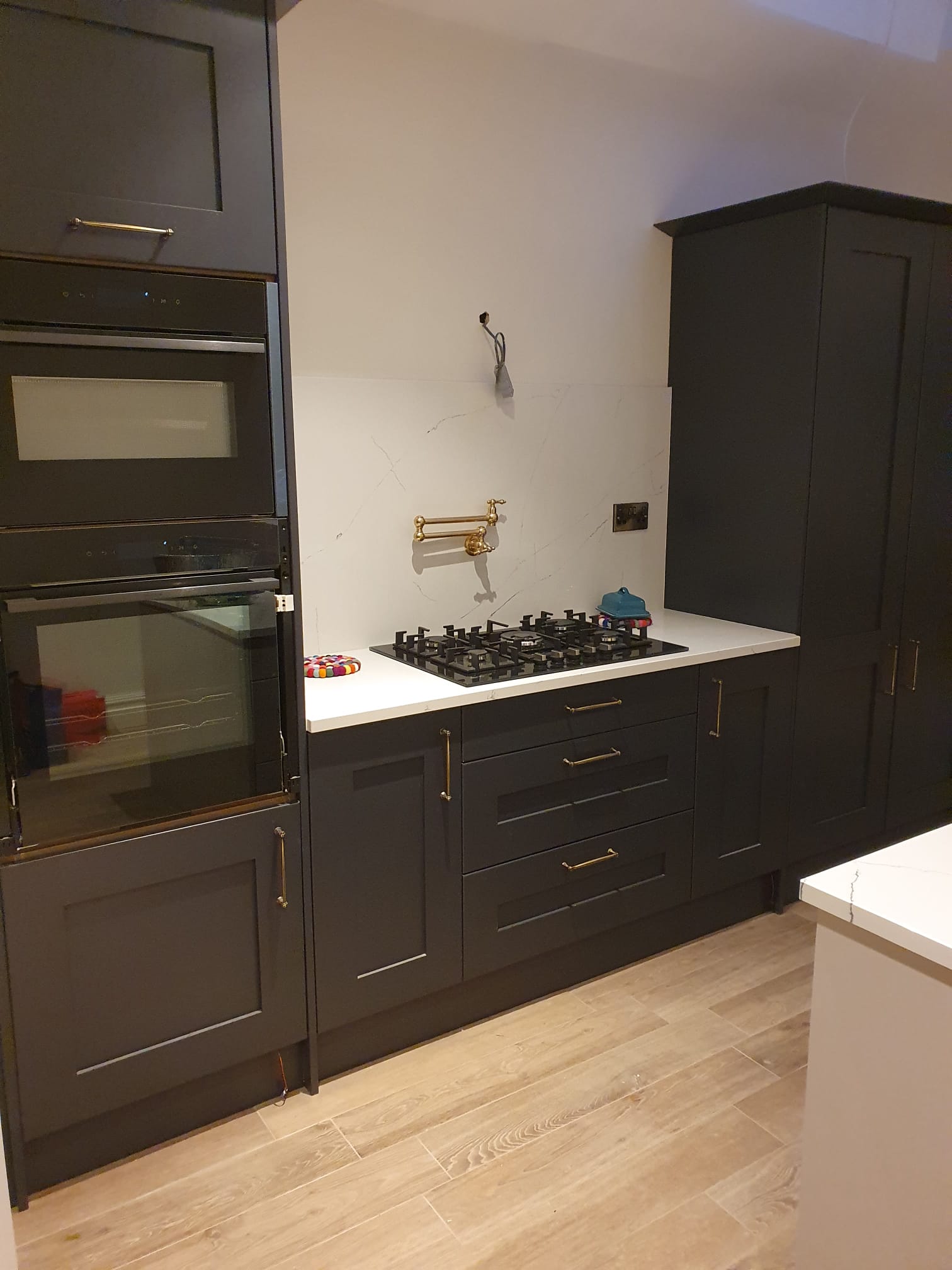 Charcoal shaker kitchen with marble splashback, brass tap and gas hob