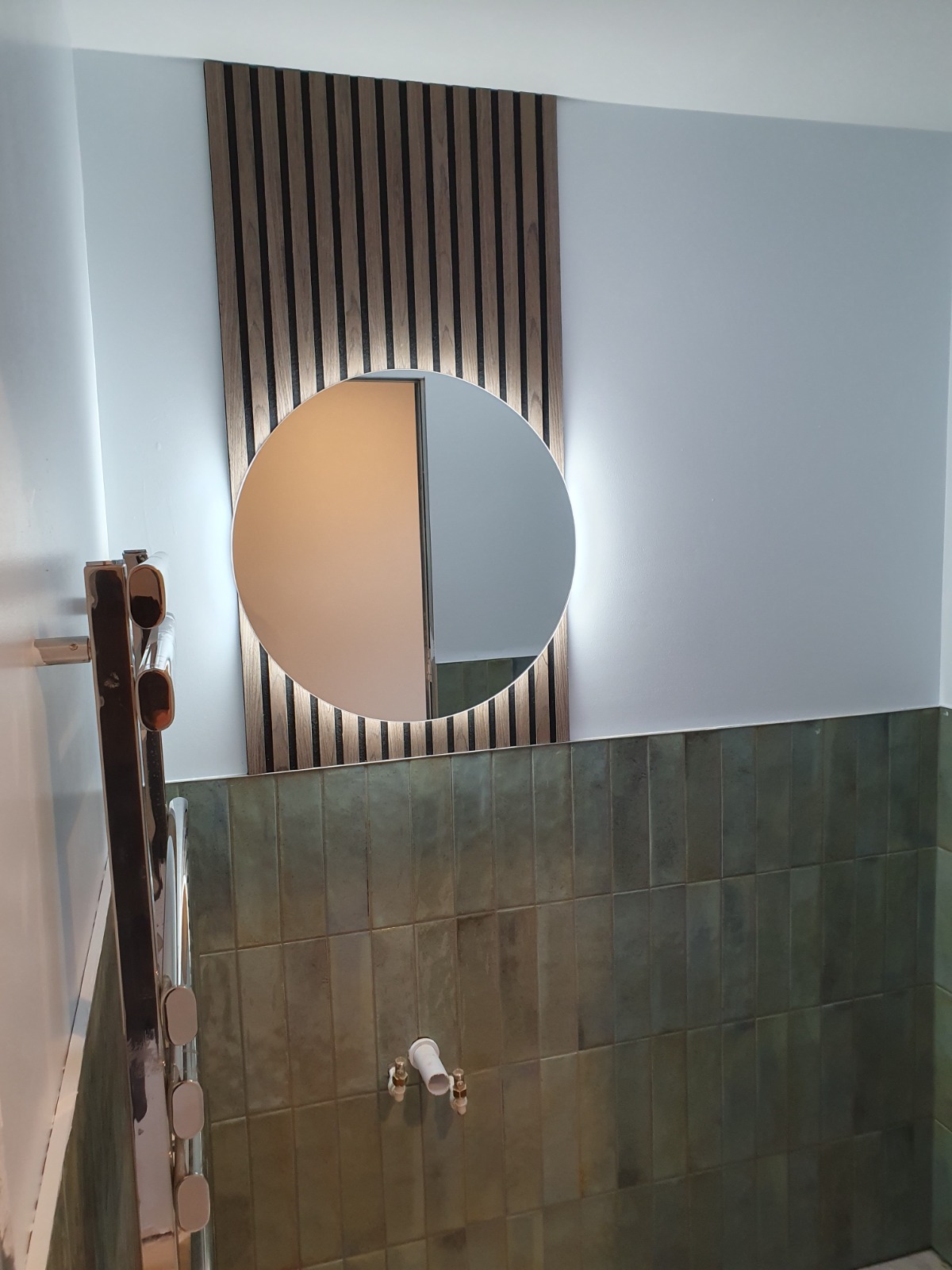 Finished bathroom with slatted wood wall and glazed green tiles